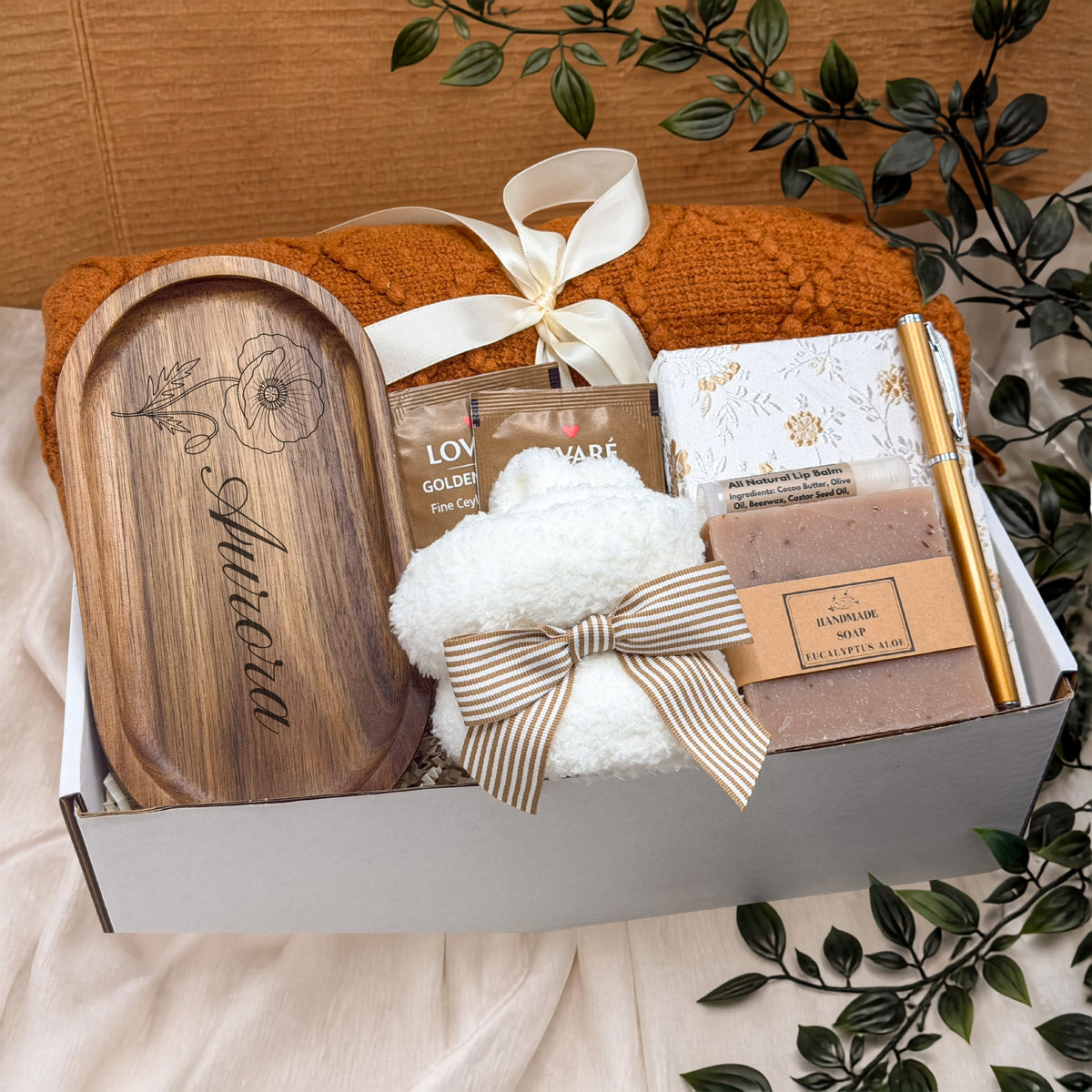 Birth flower gift box with wooden tray with custom name, handmade soap, cozy throw, herbal tea, journal and pen. Customizable text etched into the wooden jewelry tray. the box is wrapped with a ribbon to match the box and be gift ready.