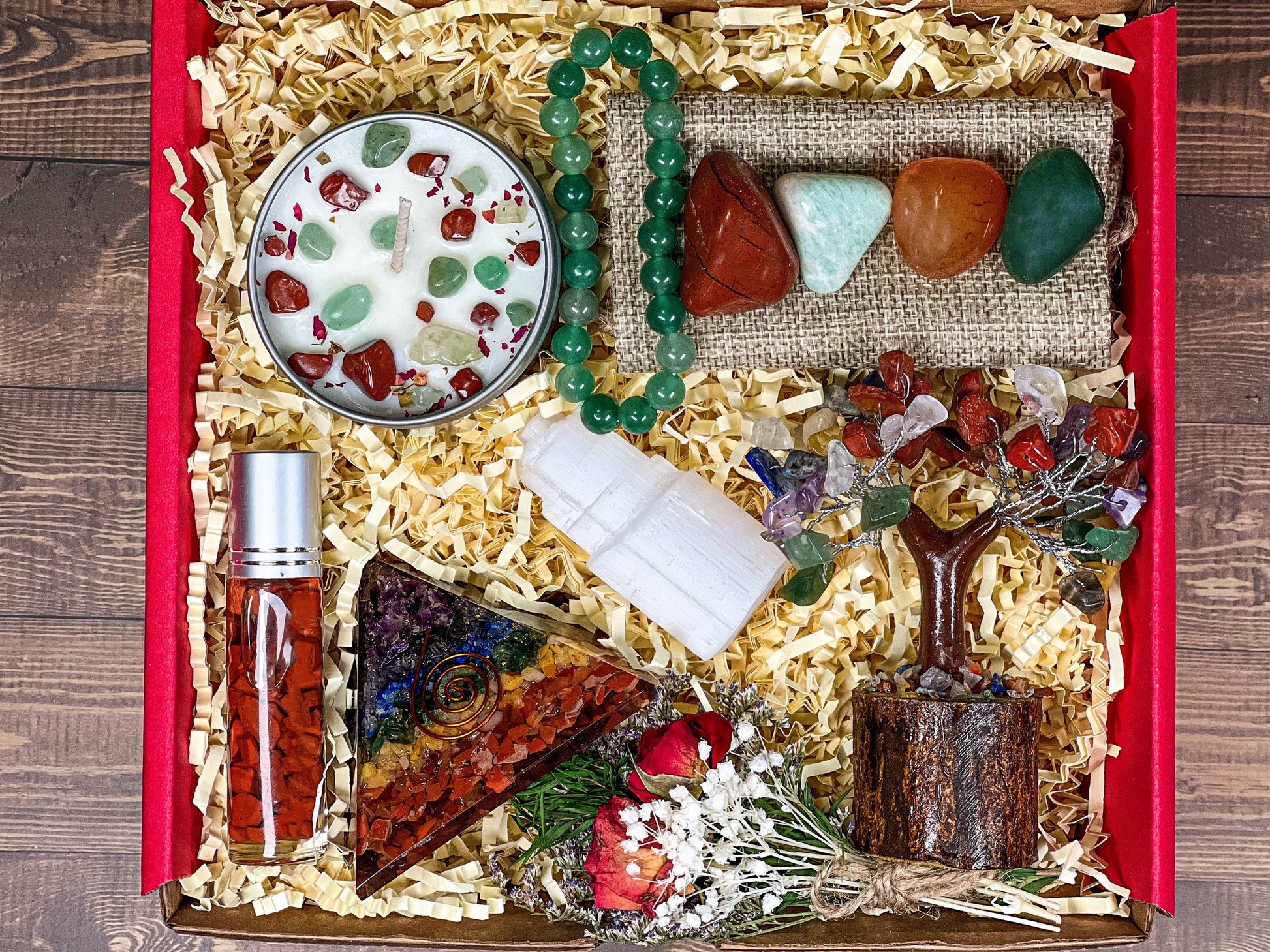 A deluxe gift box with crystals displayed, including a chakra pyramid, chakra tree, tumbled crystals, a bracelet, and a lavender scented candle.